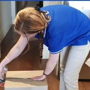 A crew member taping a carton closed on the floor of a Melbourne home