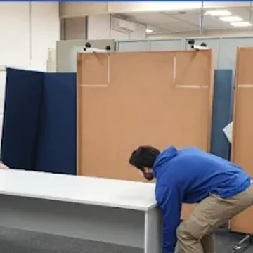 Two crew dismantling office desks during a commercial relocation